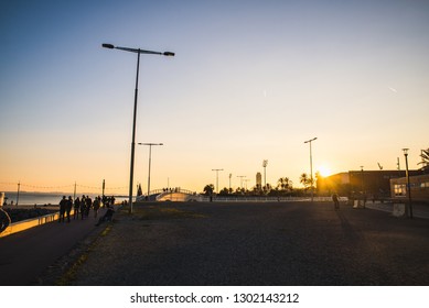 Barcelona, Spain - 05.12.2018: Beautiful Sunny Day With People Cycling And Walking Along A Street Close To The Beach