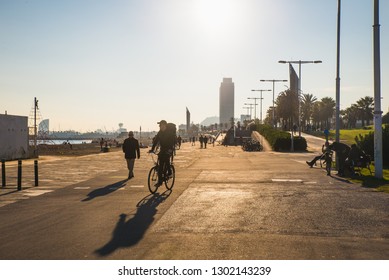 Barcelona, Spain - 05.12.2018: Beautiful Sunny Day With People Cycling And Walking Along A Street Close To The Beach