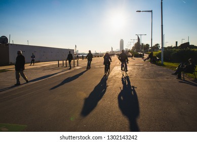 Barcelona, Spain - 05.12.2018: Beautiful Sunny Day With People Cycling And Walking Along A Street Close To The Beach