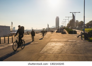 Barcelona, Spain - 05.12.2018: Beautiful Sunny Day With People Cycling And Walking Along A Street Close To The Beach