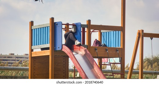 Barcelona, Spain - 06.10.2017: A Children's Slide, Slippery Dip And A Girl Resting On It