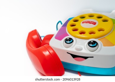 Barcelona, Spain - 12.24.2021: Children's toy landline phone with a red receiver, a dial and a smile on the body made by Fisher-Price isolated on white