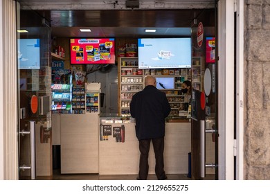 Barcelona, Spain, 20 February 2022: A Shop Assistant Behind The Counter In Front Of Shelves Containing Cigarettes And Tobacco Products