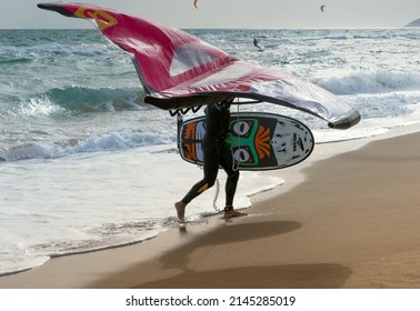 Barcelona, Spain - April 8, 2022: Silhouette of a person with wing foil equipment walking along the shore, a fashionable sport on the beaches, a hobby that mixes adrenaline and ecology.