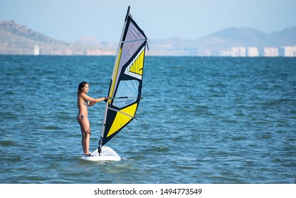 Barcelona, Spain, July 22, 2019: Windsurf Initiation. Woman learning to turn the sail. Woman standing over windsurf board and practicing sports on Summer. Winfsurfer at the sea.