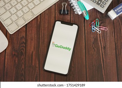 Barcelona, Spain - June 08, 2020; GoDaddy App with Stationery on a Brown Wooden Table. GoDaddy is an Internet domain registrar and web hosting company. #GoDaddy
