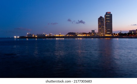 BARCELONA, SPAIN - June 27, 2021: Evening Skyline View Of Barcelona With Illuminated Buildings From Sea