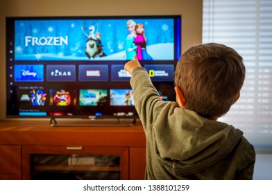 Barcelona, Spain. May 2019: Back view image of cute little boy watching the new Disney plus streaming service and pointing at the TV screen.Illustrative editorial