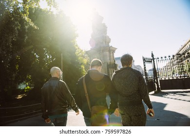 BARCELONA, SPAIN - NOV 12, 2017: Three Young Male Friends Walking To The Exit Of The Parc De La Ciutadella On A Sunny Day With Beautiful Natural Sun Flare 