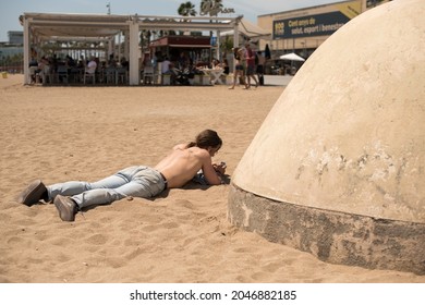 BARCELONA, SPAIN - Sep 04, 2021: A Man Sunbathing On His Back Next To A Chiringui