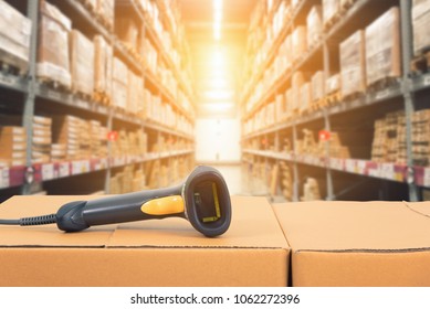 Barcode scanner in front of modern warehouse and scanning code on cardboard box