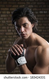 Bare chested young Malaysian boxer wearing fingerless boxing gloves