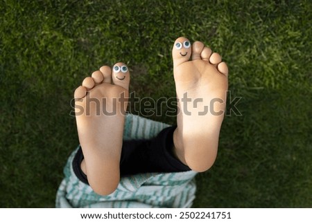 bare feet of child with funny faces painted on big toes. positive atmosphere, humor, happy childhood, joyful life. Summer holidays. walking barefoot for prevention of orthopedic problems
