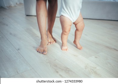 The bare feet of the child and mother are on the floor