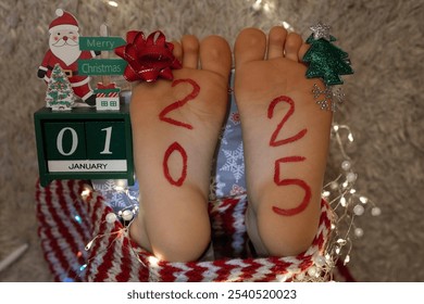 bare feet of a child on which the numbers of the new year 2025 are written. festive atmosphere on the eve of the Christmas holidays. Cheerful childhood