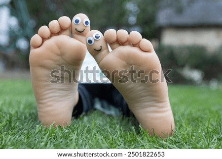 bare feet of a child with painted faces on the big toes. positive atmosphere, humor, happy childhood, joyful life. Summer vacation. prevention of orthopedic problems, foot health