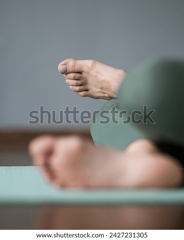 Bare feet of girl in lotus position on mat in gym. Woman's legs in fire log pose. Barefoot workout. Healthy toes and feet, ankles. Stretching, yoga, Pilates. Close-up. Side view. Soph focus.