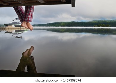 Bare Feet Hanging From A Wooden Pier Above The Water, With Space For Text Design. Enjoying The Sunrise Over The Misty Lake.