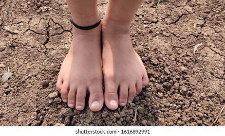 Bare Feet Of A Little Girl Wearing Black Thread As Anklet. 