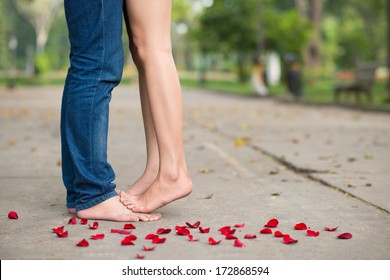Bare feet of lovers among rose petals 