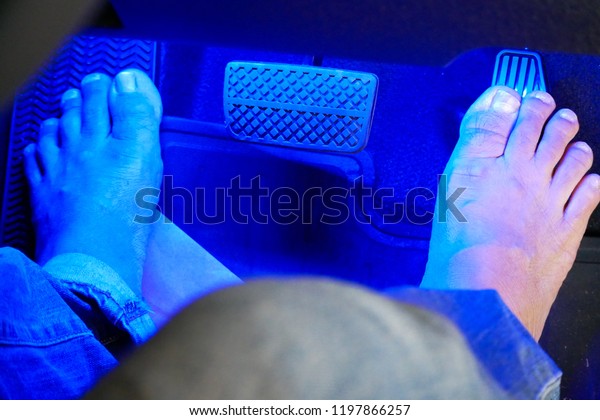 The bare feet on the car accelerator under the blue\
light.  