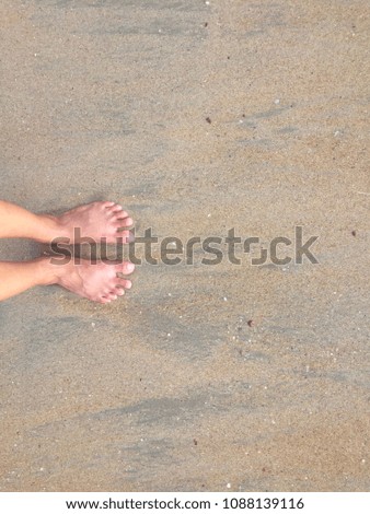 Women’s bare feet in sand on the beach top view photo