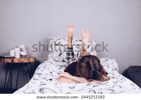 Bare feet of a teenage girl. The girl in pajamas is lying on the bed. Foot and heel