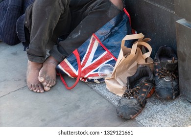 Bare Feet Of A Tramp With Old Shoes Photographed On A London Sidewalk