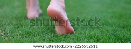 Bare feet walking on green grass in morning closeup