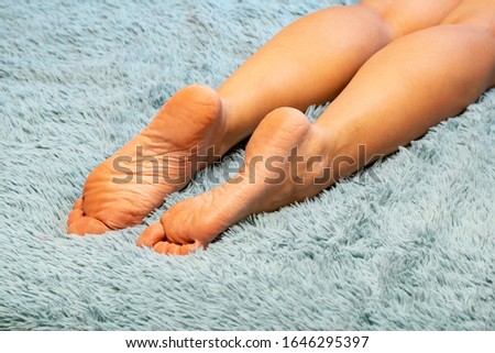 The bare feet of a young girl and her children on a fleecy blanket.