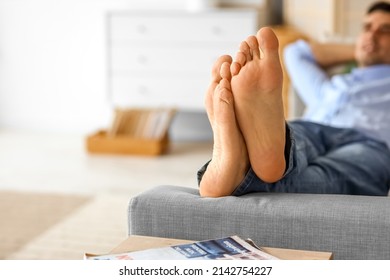 Bare feet of young man relaxing on sofa at home, closeup - Shutterstock ID 2142754227