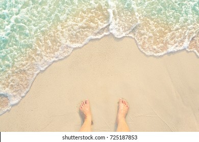 bare foot standing on the white clear water sandy beach and looking to my feet at Phuket island in Thailand