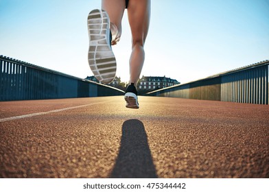 Bare legged jogger bounds towards apartments down empty road under a clear blue sky - Shutterstock ID 475344442