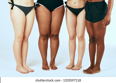 Bare Legs Of Four Happy Diverse Multiethnic Women In Swimsuits Isolated On White