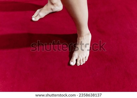 Bare legs of a girl on a red carpet.