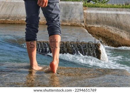 bare legs of a person in a small water layer of flowing water. 