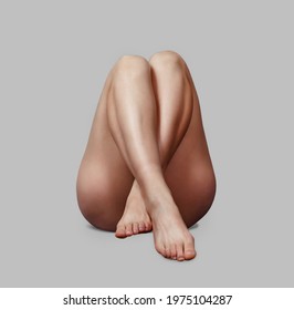 Bare Legs Of Pretty Woman Crossed On Gray Isolated Background.