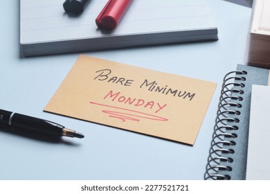 Bare Minimum Monday handwritten text on card on office desk. New work trend concept.