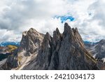 Bare peak and steep slopes of Seceda mountain range against cloudy sky. Observation deck overlooking giant ridgeline in Alps aerial view