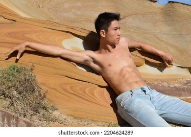 Bare-chested Young Man Lie On A Large Stone On The Beach.