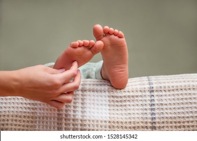 Barefeet kid on the bed. Gentle touch of baby's feet. Waking up background. Kid's feet in bed. Tickling for fun. Kids taking a rest focus on barefeet. Children's feet. Copy space. Part of series