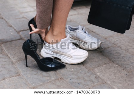 Barefoot business woman changing shoes from high heel to comfortable sneaker