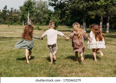Barefoot children, running on grass in a park, wearing vintage rural clothes.