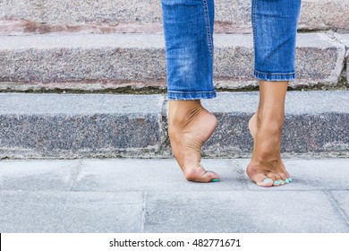 Barefoot dancer foot in jeans and a foot on the background of stone steps. Sexy female legs