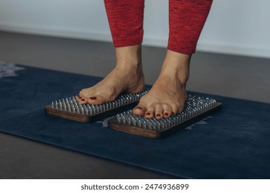 Barefoot female foot stands on a wooden board with nails for concentration practice