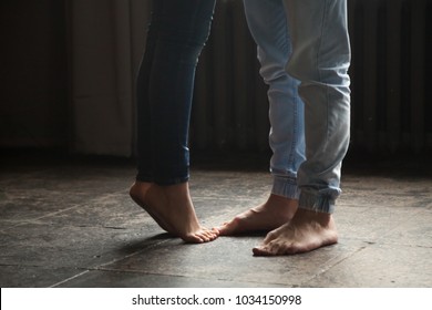 Barefoot girl standing on tiptoe to hug her man at home, sweet cute romantic couple kissing concept, male and female legs feet wearing jeans close up view, warm floor heating, femininity and delicacy