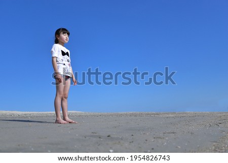 Barefoot girl standing in the sandbox