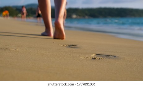 Barefoot Lady Walks On Empty Ocean Beach Wet Sand Leaving Footprints Under Blue Sky On Sunny Day Close Low Angle Backside Shot