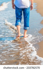 Barefoot Man In Jeans Walking On The Sea Shore