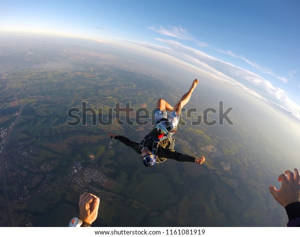 Barefoot man\
jumping from parachute at\
sunset.